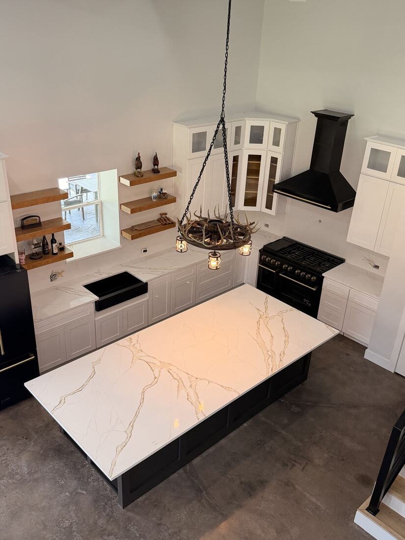 Gold-veined quartz island with a black range and farmhouse sink, seen from above