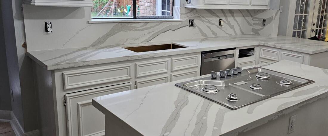 Quartz cooktop island and full backsplash with sweeping gray veins