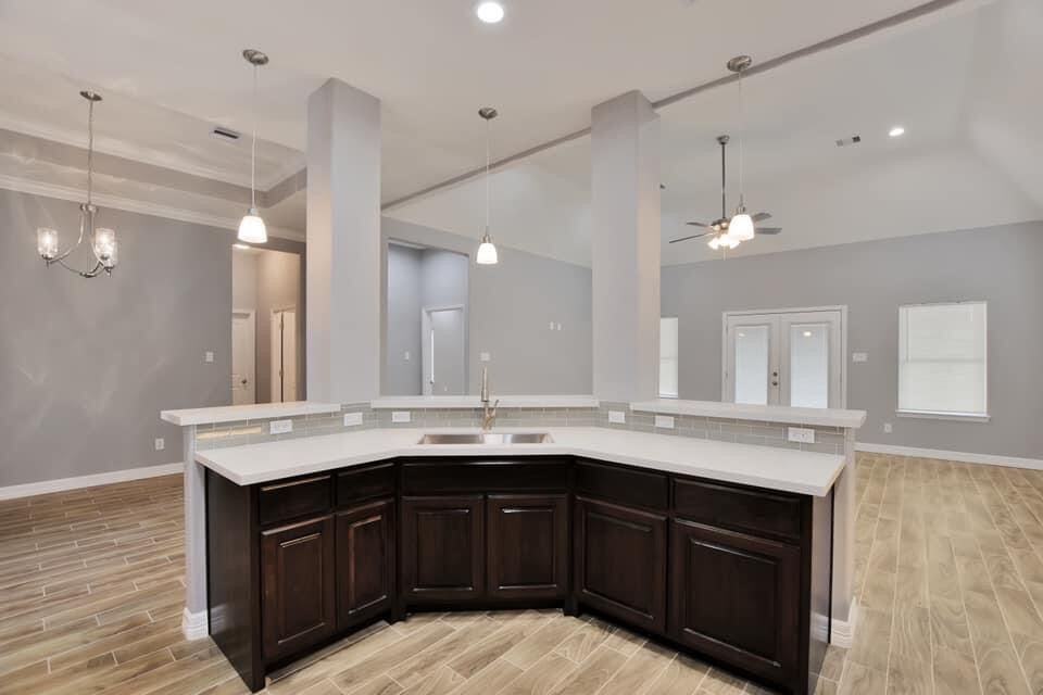 Open-plan new-build kitchen with white quartz and a dark wood island