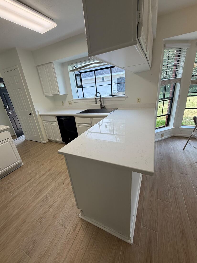 Remodeled kitchen with white quartz counters and a wraparound peninsula