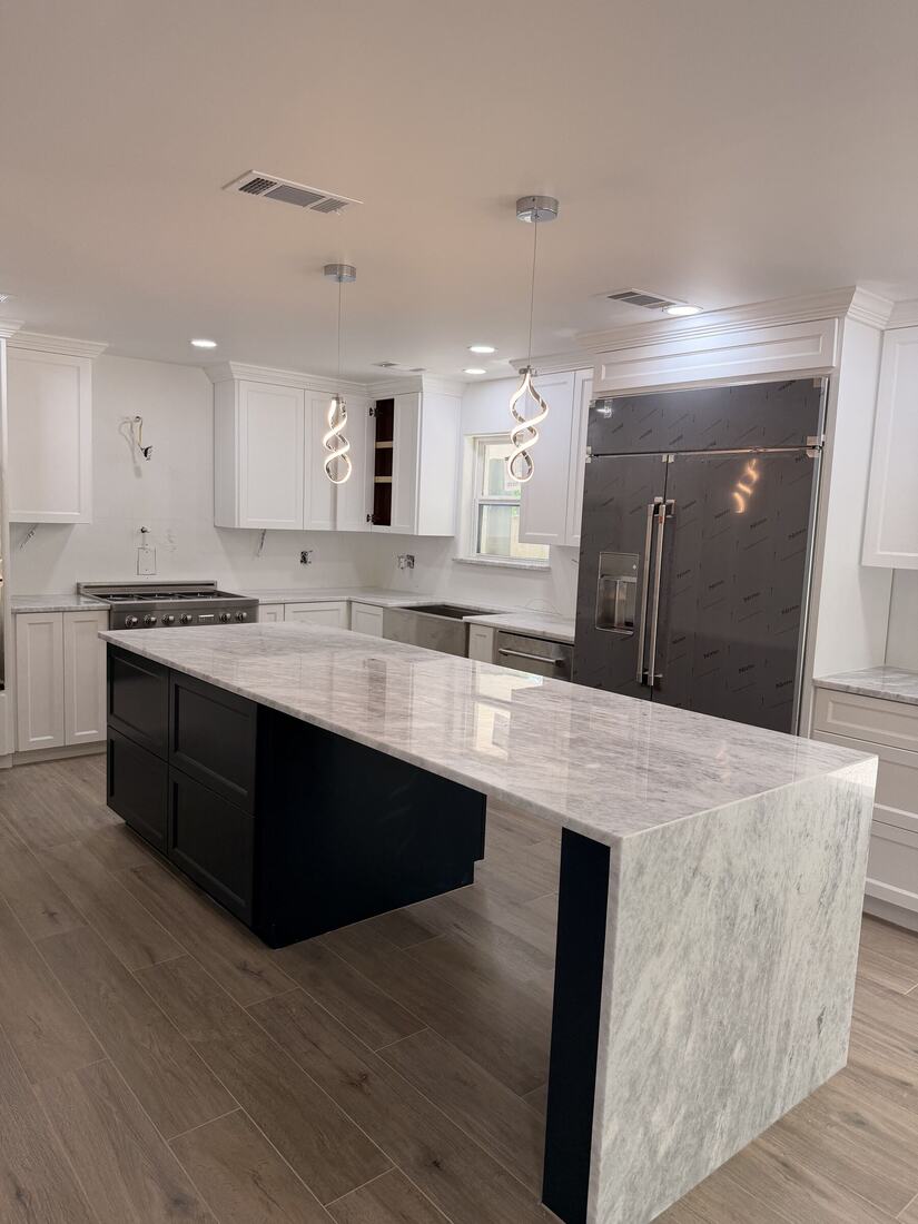 Waterfall island in veined marble-look stone with a dark base and white shaker cabinets