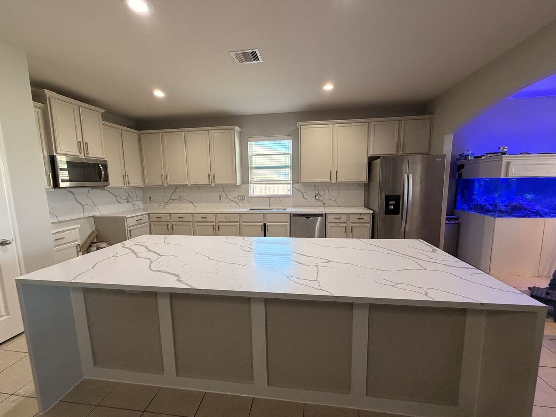 Oversized waterfall island and full backsplash in white quartz with gray veining