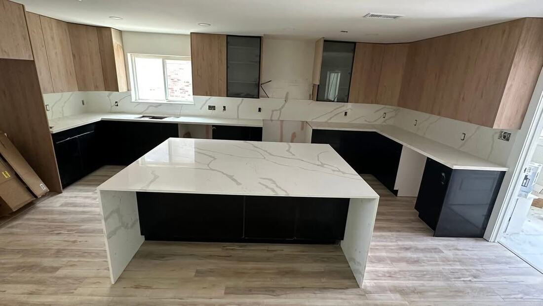 Waterfall island and quartz backsplash against black and warm wood cabinetry